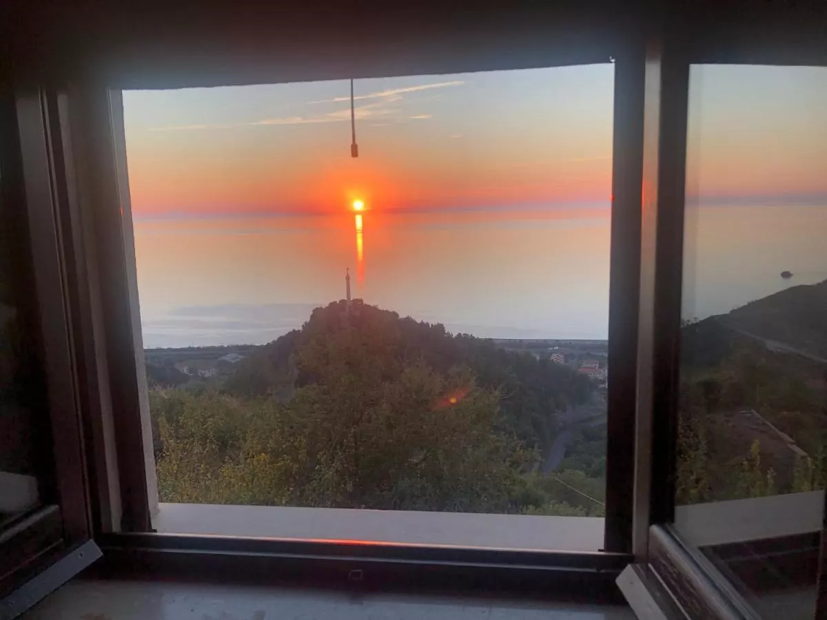 Il tramonto sul mare visto dalla finestra di una camera